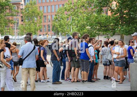 Folla di persone felici in fila all'ingresso del Reichstag in estate con edifici e alberi sullo sfondo. Foto Stock