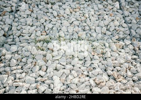 Pietre di granito dietro una griglia di metallo per rinforzare la pendenza. Pietre dietro il filo. Struttura grigia. Costruzione. Foto Stock