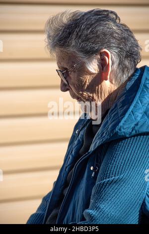 Una donna di 85 anni che soffre di depressione cronica in piedi di fronte al suo garage. Non può più guidare a causa della sua età. Foto Stock