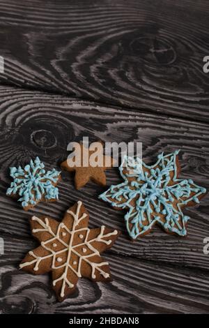 Biscotti di pan di zenzero a forma di fiocco di neve. Decorata con smalto zuccherino. Biscotti di pan di zenzero a forma di fiocco di neve. Sdraiati su tavole nere. Clo Foto Stock