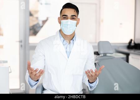 Servizi stomatologici. Ritratto di dentista arabo in maschera medica parlare alla macchina fotografica Foto Stock