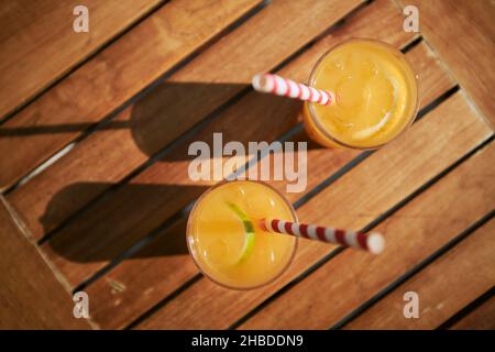 Due bevande rinfrescanti fredde. Bicchieri di cocktail con ghiaccio e frutta fresca su un tavolo di legno. Foto Stock