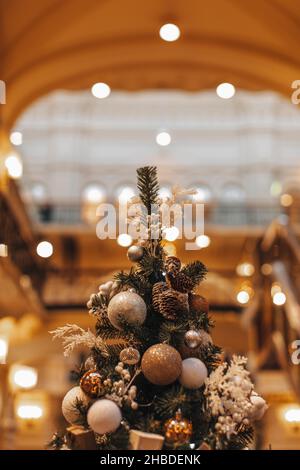 Albero di Natale decorato con palle di Natale e coni di pino. Dettagli magici, luci bokeh dorate, sfondo festoso fata Foto Stock