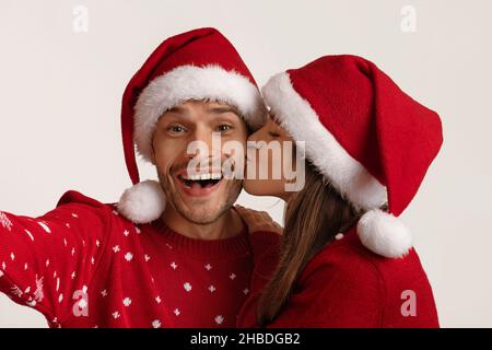 Gioia di vacanza. Coppia allegra Millennial in cappelli di Santa prendendo insieme Selfie Foto Stock