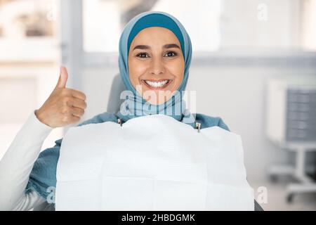 Ritratto di Happy Muslim Femminile paziente in Dental Chair mostrando Thumb Up Foto Stock