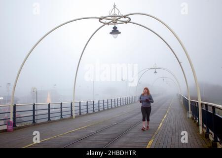 Southport, Merseyside. Meteo Regno Unito; 18th Dicembre, 2021. Densa nebbia dopo la notte più fredda dell'anno nella città costiera nord-occidentale. I residenti del resort si allenano al mattino sul lungomare in condizioni di nebbia fredda. Credit; MediaWordImages/AlamyLiveNews Foto Stock