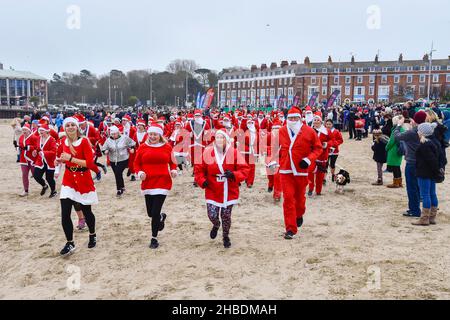 Weymouth, Dorset, Regno Unito. 19th dicembre 2021. Centinaia di corridori vestiti come Babbo Natale prendono parte all'annuale The Chase the Pudding pre-chistmas correre sulla spiaggia di Weymouth nel Dorset. L'evento annuale sta raccogliendo fondi per la carità Mackaness fiducia. L'inseguimento si mette in atto. Picture Credit: Graham Hunt/Alamy Live News Foto Stock