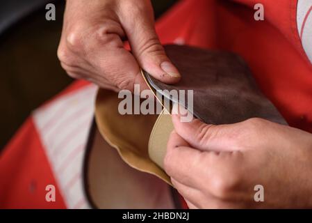 Le mani del calzolaio cucire la fodera alla scarpa in pelle fatta a mano in officina. Produzione di scarpe artigianali. Concetto di piccola impresa Foto Stock