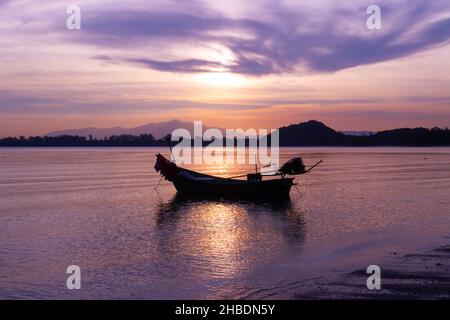 Barca di pescatore sulla spiaggia con silhouette di luce prima del tramonto e montagna sfondo Asia Thailandia Foto Stock