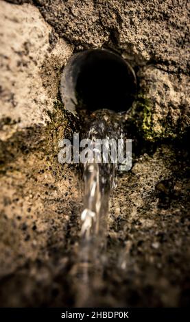 Una vista di acqua che scorre giù del tubo nelle rocce Foto Stock