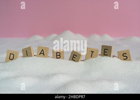 Le lettere su piccoli tasselli di legno che formano la parola diabete su una distesa di zucchero Foto Stock