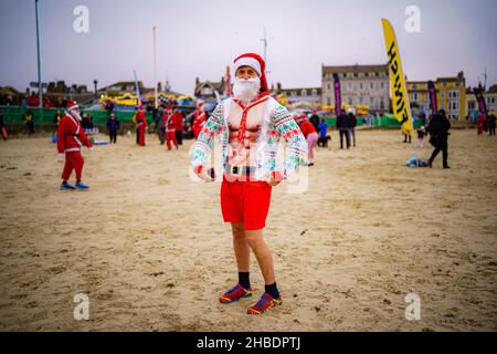 Un uomo sulla spiaggia di Weymouth, partecipa alla gara annuale Chase the Pudding, dove i concorrenti inseguono un corridore vestito come pudding di Natale mentre corrono un percorso 5km lungo la spiaggia. Data foto: Domenica 19 dicembre 2021. Foto Stock