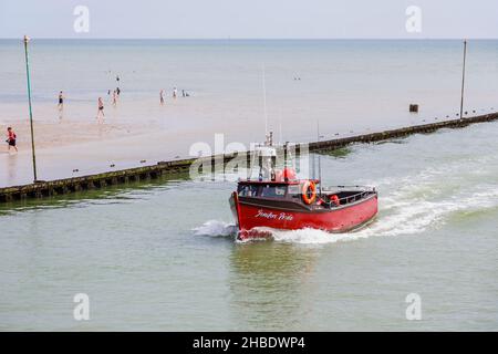 Piccola barca rossa da pesca Jenifer's Pride entra nel fiume Arun da East Beach, Littlehampton, una località turistica della costa meridionale nel Sussex occidentale in estate Foto Stock