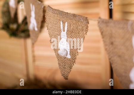 Decorazioni di pasqua. Ghirlanda con uova e del viola e il colore bianco, ghirlanda con conigli contro lo sfondo di una parete di legno scuro. Foto Stock