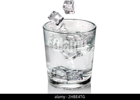 I cubetti di ghiaccio cadono con spruzzi in un bicchiere d'acqua dolce, isolato su bianco Foto Stock