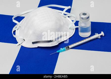 Finland flag, maschera facciale n95, siringa con ago e flaconcino. Concetto di distribuzione del vaccino del coronavirus Covid-19, carenza di approvvigionamento e crisi sanitaria Foto Stock