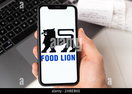 Applicazione Food Lion di supermercato e negozio di alimentari in uno smartphone. Un uomo ha in mano uno smartphone con app per lo shopping e un notebook in background. Novembre 2021, San Francisco, USA Foto Stock