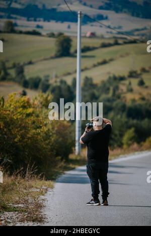 Una foto verticale di un giovane fotografo con la sua macchina fotografica in natura, Bosnia-Erzegovina Foto Stock