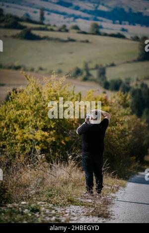 Una foto verticale di un giovane fotografo con la sua macchina fotografica in natura, Bosnia-Erzegovina Foto Stock