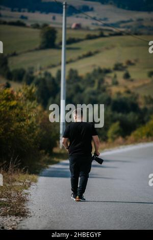 Una foto verticale di un giovane fotografo con la sua macchina fotografica in natura, Bosnia-Erzegovina Foto Stock