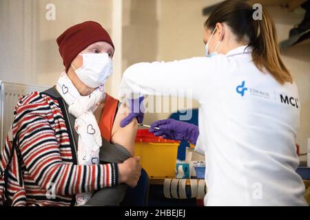 Naklo, Slovenia. 19th Dic 2021. Un operatore medico somministra un vaccino COVID-19 a una donna in un'unità mobile di vaccinazione durante una campagna di promozione della vaccinazione a livello nazionale. In Slovenia inizia una campagna di promozione della vaccinazione COVID-19 di cinque giorni, in cui 62 centri di vaccinazione nel paese e le unità di vaccinazione mobile lavorano straordinari, il personale della protezione civile e della Croce Rossa fornisce il trasporto gratuito ai siti di vaccinazione e vengono istituiti centri di vaccinazione notturna. Credit: SOPA Images Limited/Alamy Live News Foto Stock