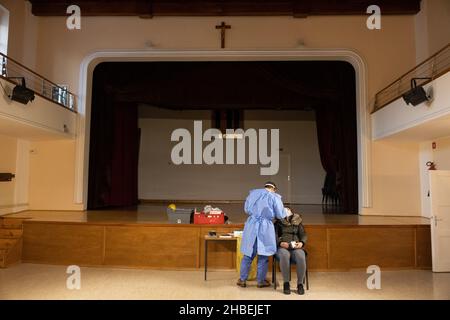 Naklo, Slovenia. 19th Dic 2021. Una donna viene testata per la ricerca di COVID-19 in un centro culturale, uno dei 62 centri di vaccinazione che lavorano straordinari durante una campagna di promozione della vaccinazione a livello nazionale. In Slovenia inizia una campagna di promozione della vaccinazione COVID-19 di cinque giorni, in cui 62 centri di vaccinazione nel paese e le unità di vaccinazione mobile lavorano straordinari, il personale della protezione civile e della Croce Rossa fornisce il trasporto gratuito ai siti di vaccinazione e vengono istituiti centri di vaccinazione notturna. Credit: SOPA Images Limited/Alamy Live News Foto Stock