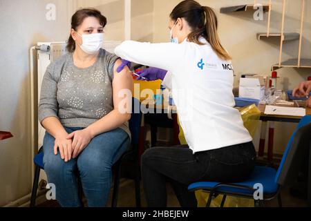 Naklo, Slovenia. 19th Dic 2021. Un operatore medico somministra un vaccino COVID-19 a una donna in un'unità mobile di vaccinazione durante una campagna di promozione della vaccinazione a livello nazionale. In Slovenia inizia una campagna di promozione della vaccinazione COVID-19 di cinque giorni, in cui 62 centri di vaccinazione nel paese e le unità di vaccinazione mobile lavorano straordinari, il personale della protezione civile e della Croce Rossa fornisce il trasporto gratuito ai siti di vaccinazione e vengono istituiti centri di vaccinazione notturna. Credit: SOPA Images Limited/Alamy Live News Foto Stock