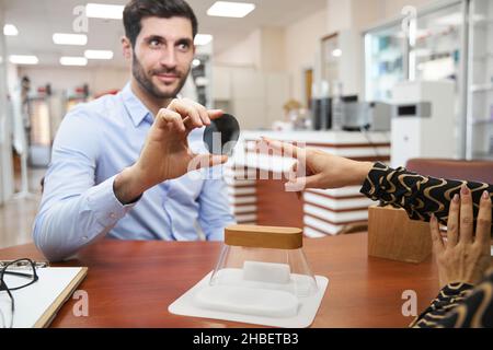 Maschio che tiene lenti occhiali da sole nel tavolo di consegna Foto Stock