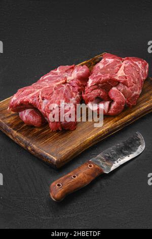 Carne di agnello crudo arrotolata disossata al collo sul tagliere Foto Stock