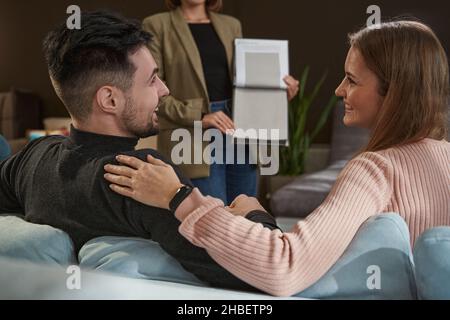 Due acquirenti gioiosi che scelgono il materiale per la tappezzeria del divano Foto Stock