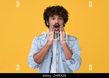 Scioccato sorpreso giovane indiano isolato su sfondo giallo. Foto Stock
