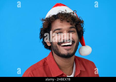 Felice giovane uomo indiano che indossa santa Hat isolato su sfondo blu. Foto Stock