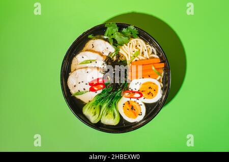 Spaghetti asiatici ramen in brodo con carne alla lingua di manzo, funghi e  uova sott'aceto in ciotola su sfondo verde e arancione Foto stock - Alamy