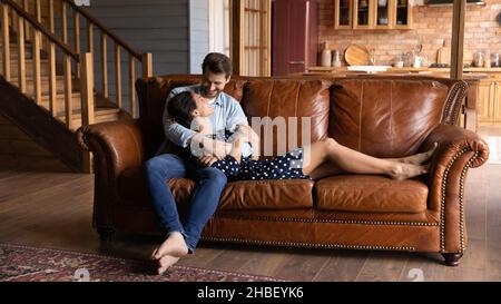 Affettuoso felice coppia di famiglia giovane rilassarsi su un comodo divano. Foto Stock