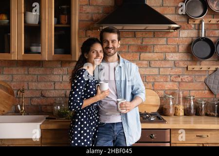 Ritratto di legame millennial amorevole coppia di famiglia in posa in cucina. Foto Stock