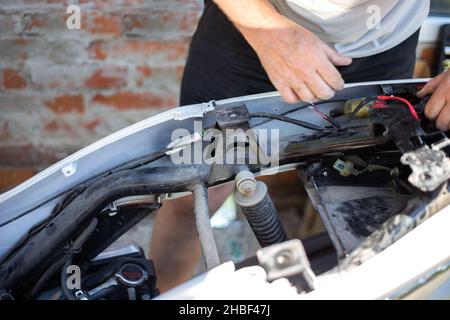 Un uomo sta riparando una moto. Motocicletta smontata. Foto Stock