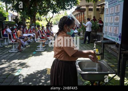 Denpasar, Indonesia. 15th Dic 2021. Una studentessa si lava la mano prima di entrare in una linea per la vaccinazione. La Scuola elementare 33 di Dangin Puri, Denpasar, Bali, ha iniziato la vaccinazione di Covid-19 per studenti di 6-11 anni come Indonesia continua ad aumentare il numero di vaccinazioni per prevenire il coronavirus Covid-19 da ulteriore diffusione. (Foto di Dicky Bisinglasi/SOPA Images/Sipa USA) Credit: Sipa USA/Alamy Live News Foto Stock