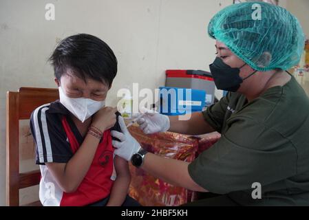 Denpasar, Bali, Indonesia. 15th Dic 2021. Un operatore sanitario somministra una dose del vaccino Sinovac covid-19 ad uno studente. La Scuola elementare 33 di Dangin Puri, Denpasar, Bali, ha iniziato la vaccinazione di Covid-19 per gli studenti di 6-11 anni, in quanto l'Indonesia continua ad aumentare il numero di vaccinazioni dei cittadini al fine di impedire che il coronavirus Covid-19 si diffonda ulteriormente. (Credit Image: © Dicky Bisinglasi/SOPA Images via ZUMA Press Wire) Foto Stock