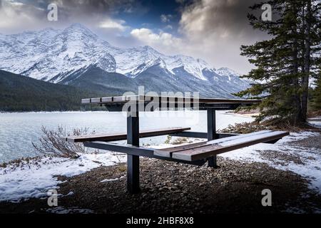 Un tavolo da picnic in legno con vista sui laghi Spray nelle Montagne Rocciose canadesi vicino a Banff. Foto Stock