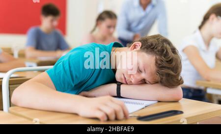 Lo studente stanco si è addormentato sulla scrivania in classe Foto Stock