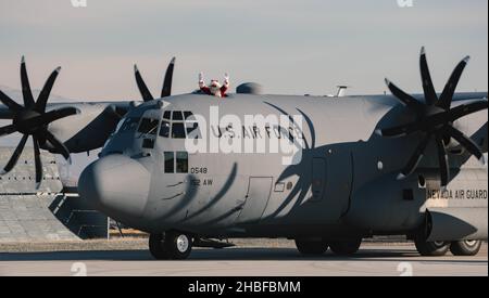 Babbo Natale si esula dalla cima di un aereo C-130 Hercules mentre arriva alla base della Guardia Nazionale dell'aria del Nevada, Reno, Nevada, 18 dicembre 2021. Il sig. Claus e due dei suoi elfi hanno ottenuto un giro dall'Ala dell'Airlift 152nd a Reno per aiutarlo a diffondere il gheer di festa ai guardiani del Nevada e alle loro famiglie. (STATI UNITI Air National Guard foto di Airman First Class Thomas Cox) Foto Stock