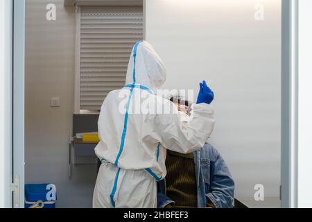 Donna nera seduta per ottenere un test rapido (SARS-COV-2 Rapid Antigen Test) prima di salire a bordo nell'aeroporto di Faro, Portogallo, da un'infermiera che tiene un tampone nasale Foto Stock