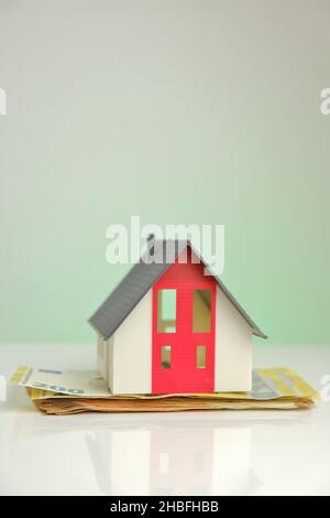 Acquisto e costruzione di una casa. Casa e soldi. Casa mock con tetto grigio sulle banconote in euro Foto Stock