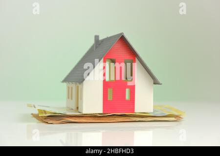 Acquisto e costruzione di una casa. Casa e soldi. Casa mock con tetto su sfondo banconote in euro. Mercato immobiliare. Prestito immobiliare. Foto Stock