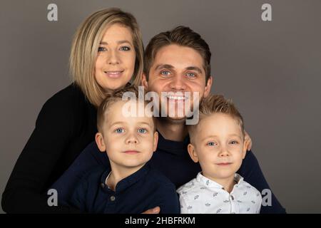 Una famiglia felice che guarda la fotocamera di fronte a uno sfondo grigio