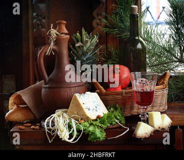 Natura morta con formaggio, vino rosso e ananas su sfondo ligneo Foto Stock