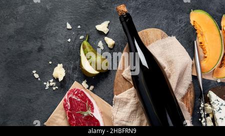 Vino rosso con antipasti su sfondo grigio. Bevande alcoliche tradizionali. Vista dall'alto, disposizione piatta, spazio di copia Foto Stock