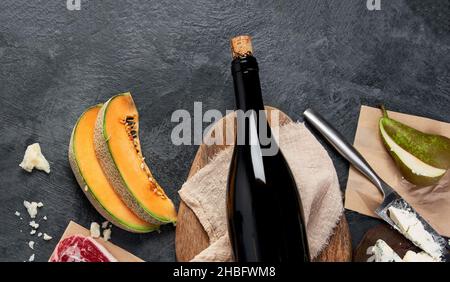 Vino rosso con antipasti su sfondo grigio. Bevande alcoliche tradizionali. Vista dall'alto, disposizione piatta, spazio di copia Foto Stock