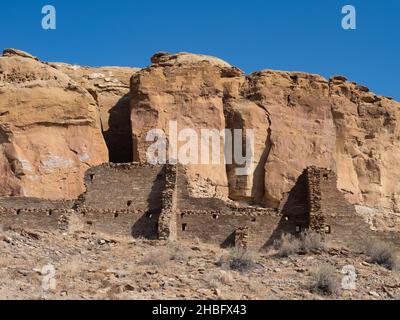 Rovine di Hungo Pavi al Chaco Culture National Historic Park nel New Mexico contro le scogliere di roccia rossa. Foto Stock