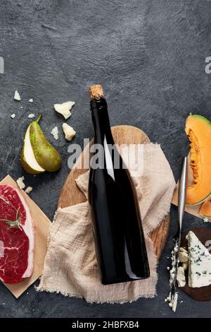 Vino rosso con antipasti su sfondo grigio. Bevande alcoliche tradizionali. Vista dall'alto, disposizione piatta, spazio di copia Foto Stock